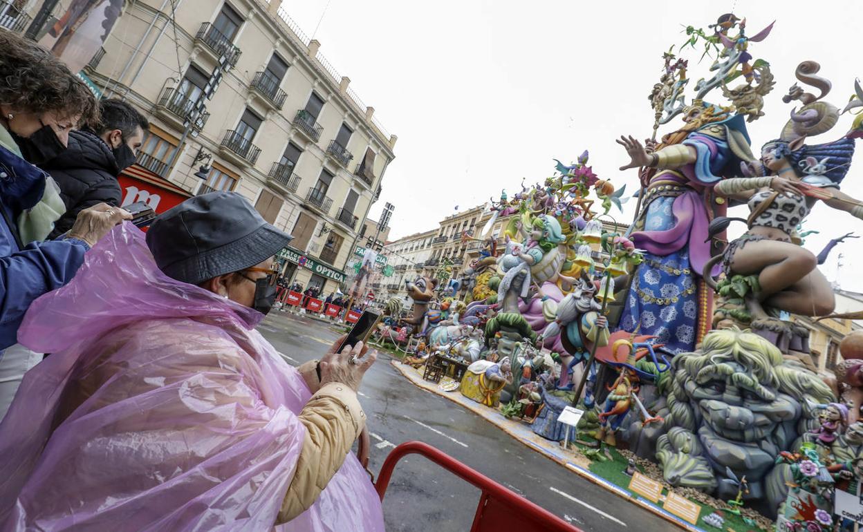 Una mujer con impermeable fotografía a una de las fallas que arderán hoy en Valencia. 