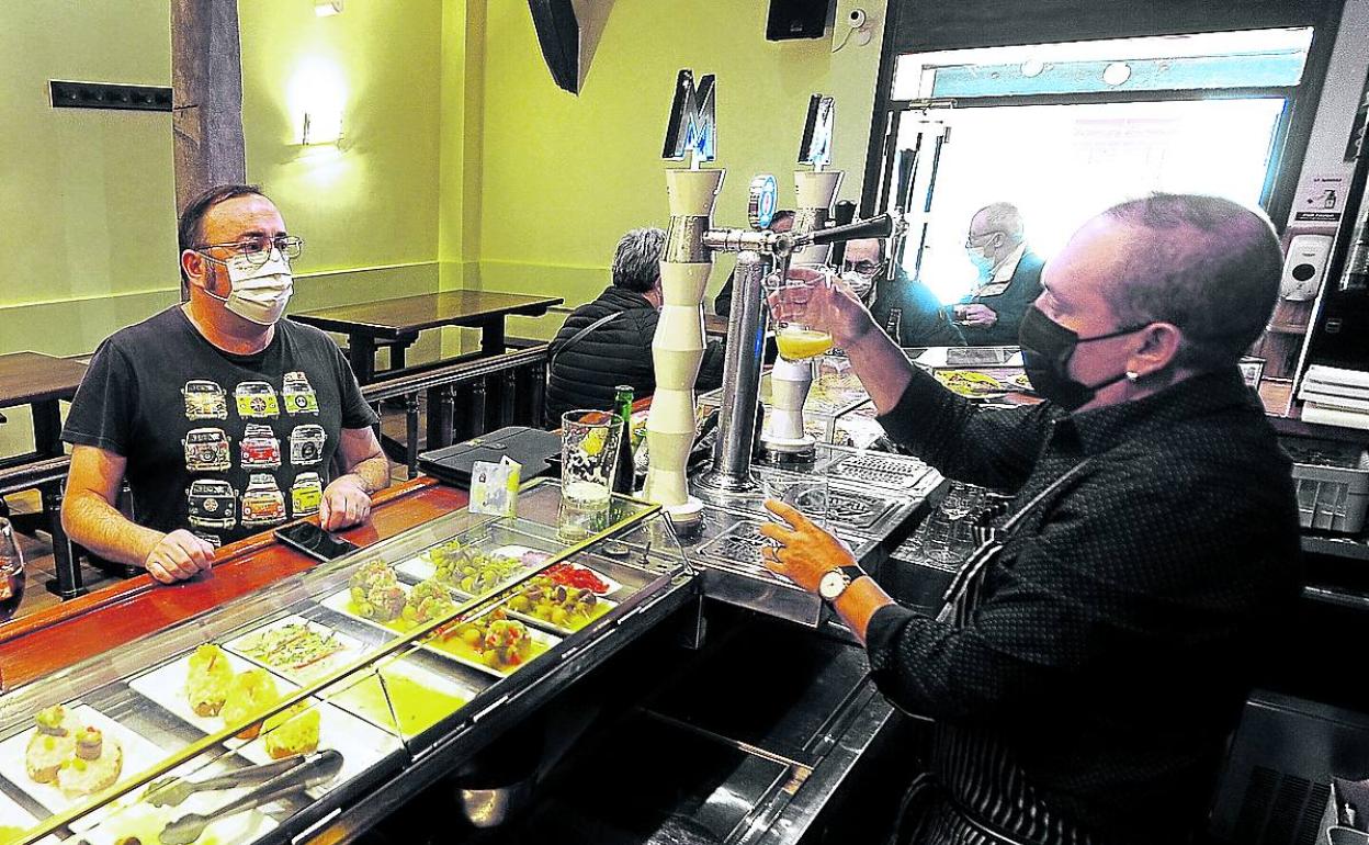Un hostelero sirve cerveza a un cliente en un local de Vitoria.