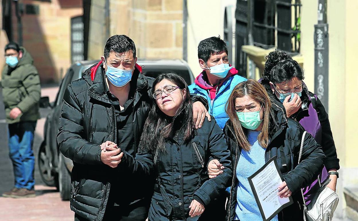 Los padres de Erika Yunga, René y Alba, arropados por otros familiares a la entrada del velatorio.