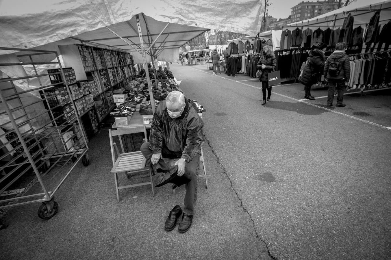 Un hombre se prueba unos zapatos en el mercado ambulante que se levanta cada miércoles en el parking, que cuenta con una zona reservada, y muy solicitada a raíz de la pandemia, para caravanas.