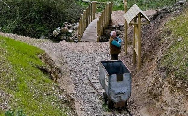 Un hombre lee un panel informativo junto a una vieja vagoneta.