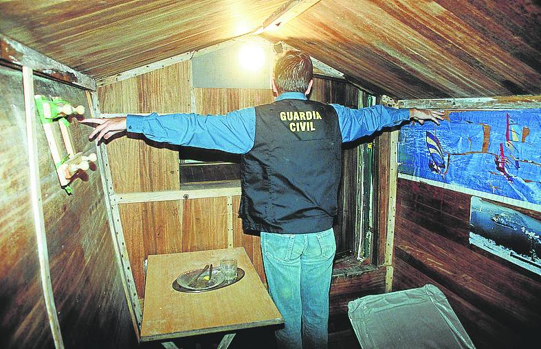 Un guardia civil toca las dos paredes del zulo estirando las manos. 