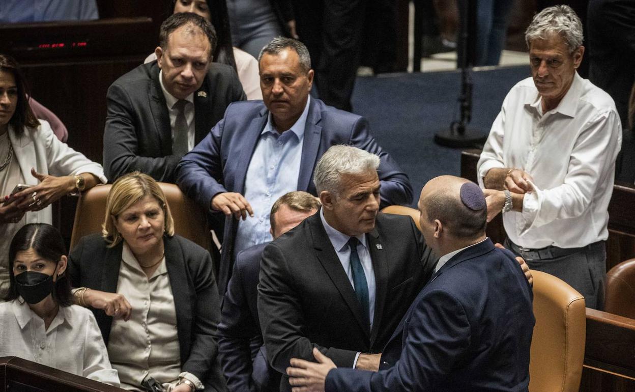 El ministro de Exteriores, Yair Lapid, (i) y el primer ministro, Naftali Bennet, (d) estrechan sus manos este jueves, tras la disolución del Parlamento de Israel