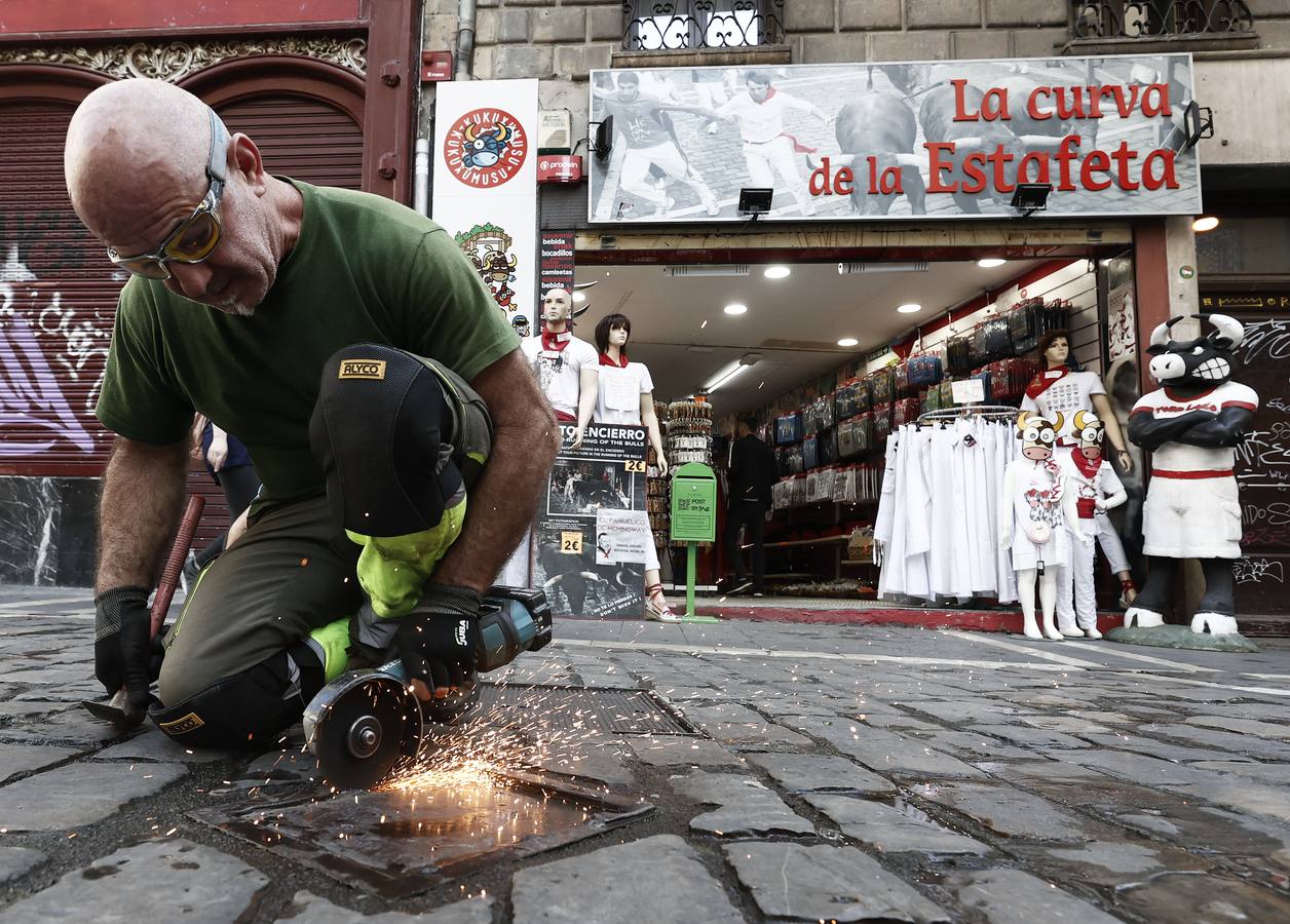 Un operario sierra el punto de soldadura de una de las tapas situadas en el recorrido de los encierros que albergaran los postes sobre los que irán colocadas las tablas que conformaran el vallado en el tramo de Mercaderes