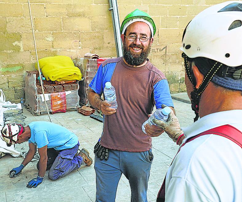 Txus de Sa reparte agua entre sus peones, empleados en la reforma de la iglesia de Lapuebla de Labarca.