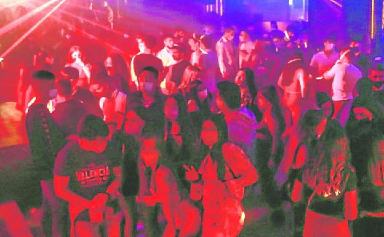 Decenas de jóvenes bailan en una discoteca abarrotada. 