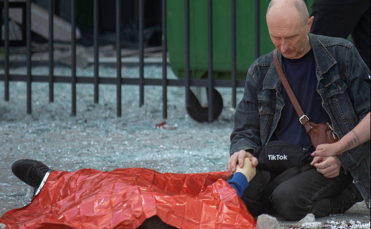 Un padre se arrodilla ante el cadáver de su hijo en Járkov (Ucrania). 