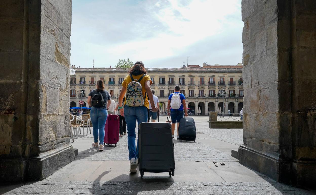 Un grupo de turistas entra con sus maletas a la plaza de España. 