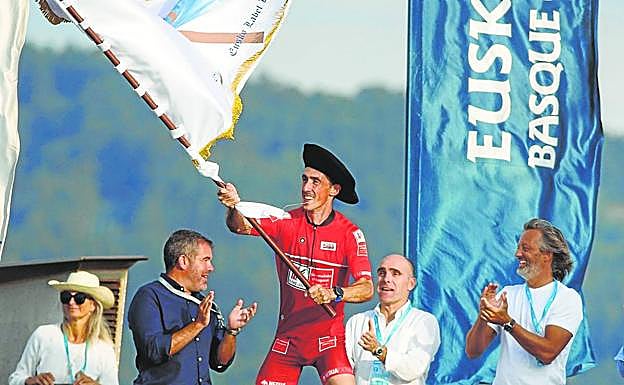 Gorka Aranberri ondea la bandera desde el barco de la organización. 