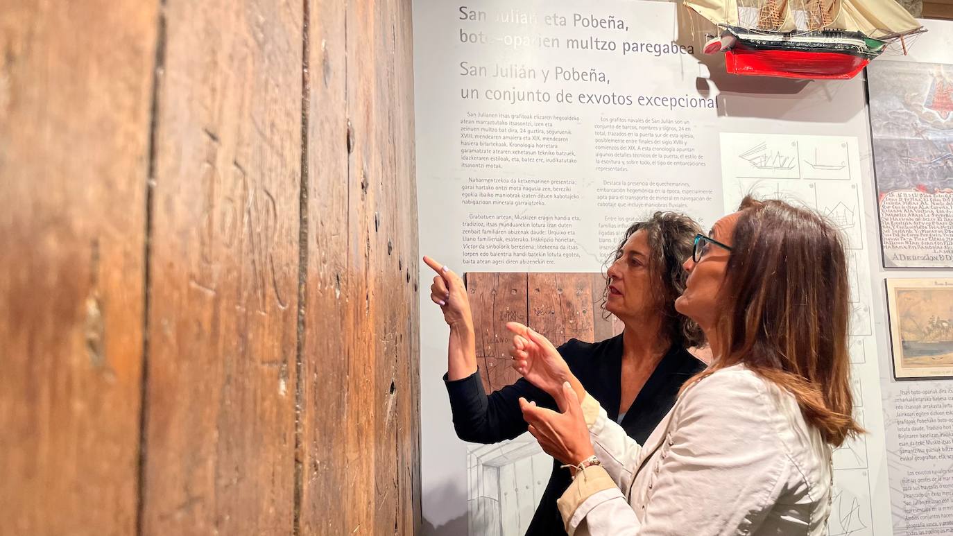 La diputada de Cultura, Lorea Bilbao, y la directora de El Pobal, Marta Zabala, observan los grabados sobre la puerta restaurada.