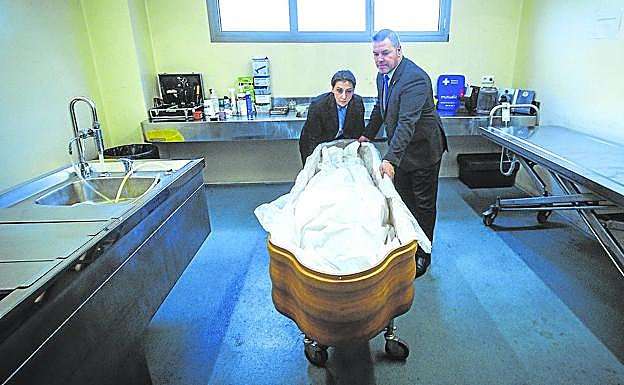 Los funerarios introducen a un fallecido en el ataúd en la sala de preparación. 