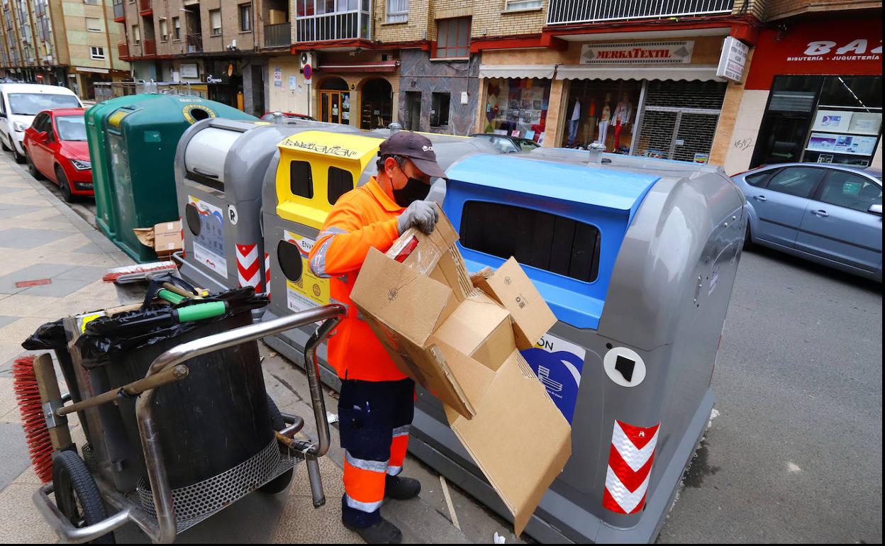 Un trabajador de limpieza deposita cartón en los contenedores. 