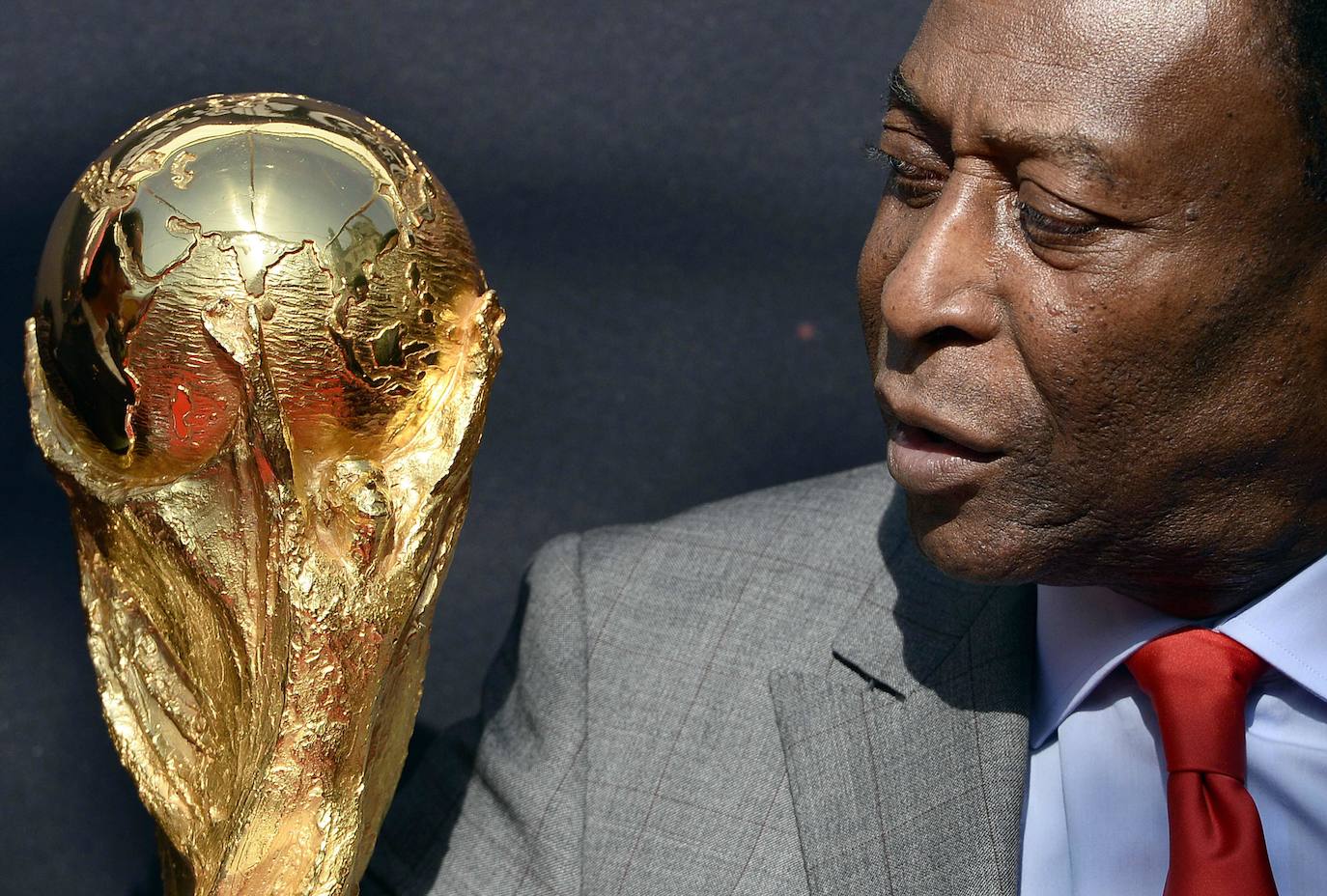 En esta foto de archivo tomada el 9 de marzo de 2014, la leyenda del fútbol brasileño, Pelé, mira el trofeo de la Copa Mundial de la FIFA durante un evento de la FIFA frente al Hotel de Ville en París.