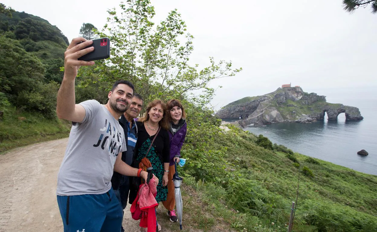 Un grupo de turistas se saca un selfie con la imagen de San Juan de Gaztelugatxe de fondo. 
