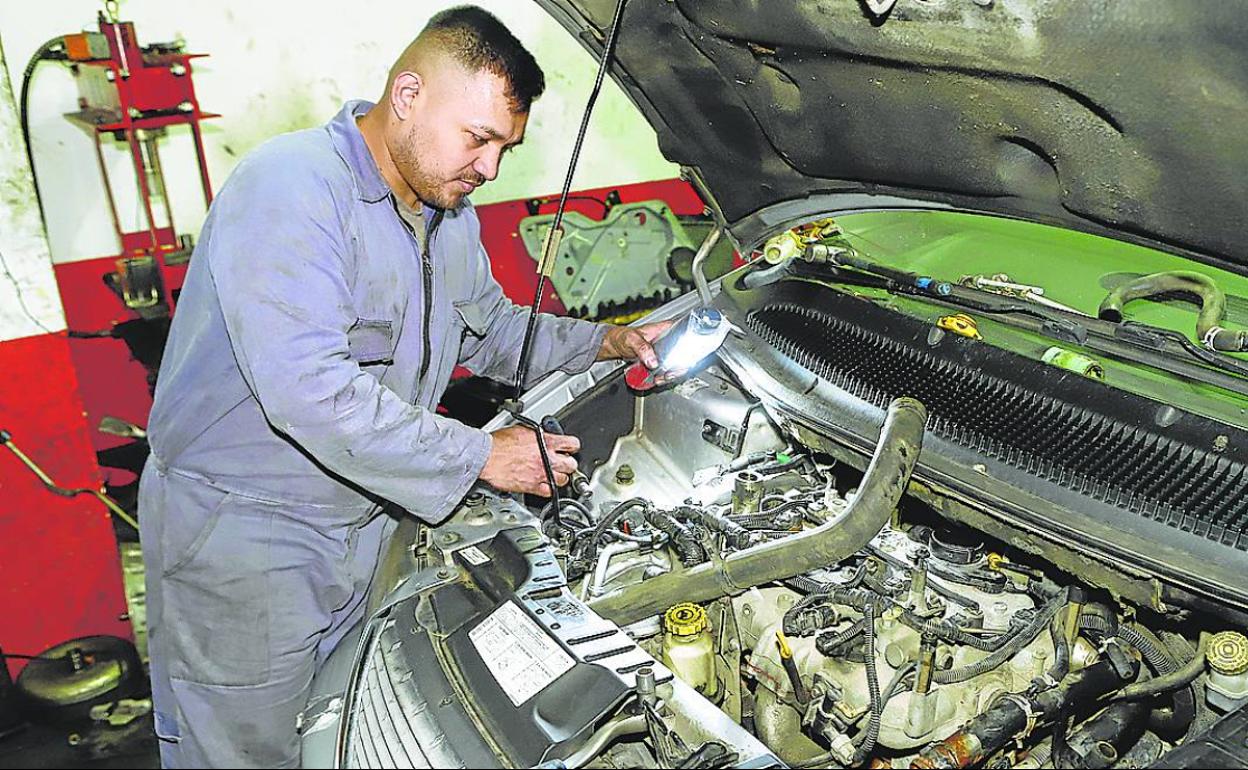 El empleado de un taller de reparación revisa un automóvil. 