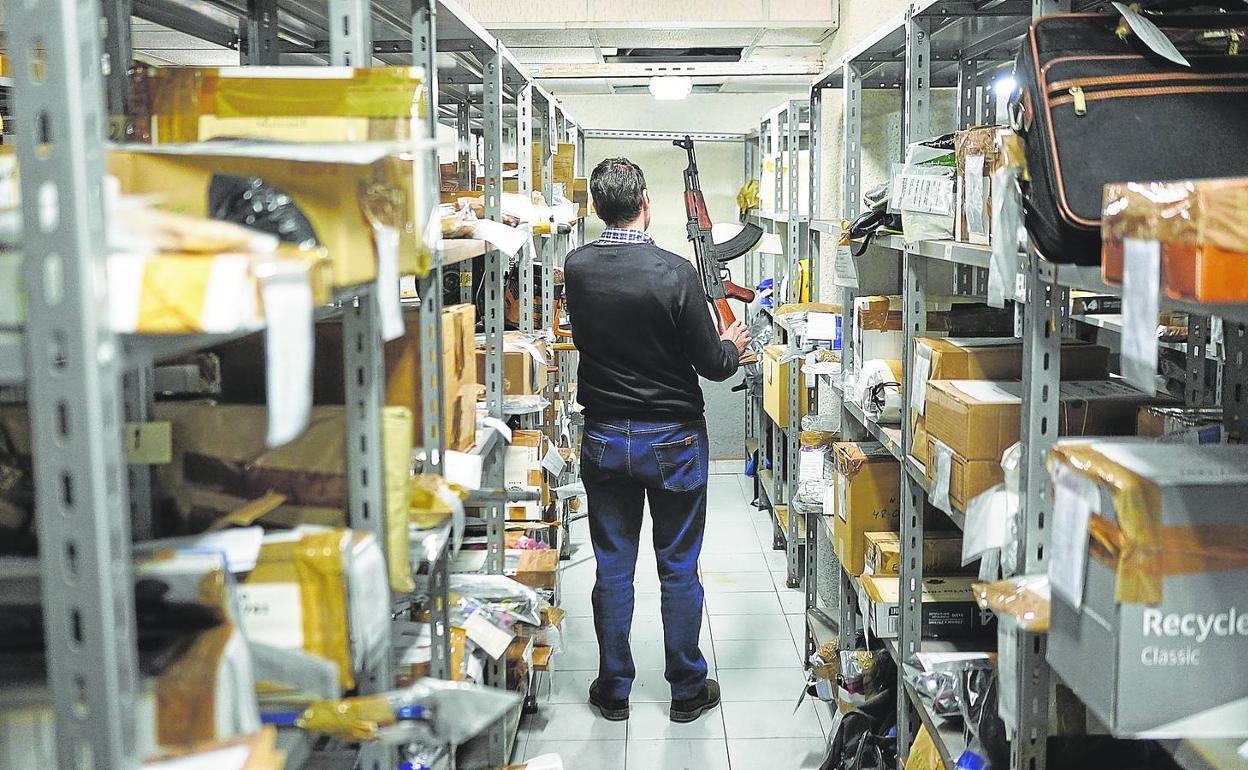 Un funcionario del depósito de efectos judiciales de Bilbao coloca en su sitio una réplica de un arma de fuego. 