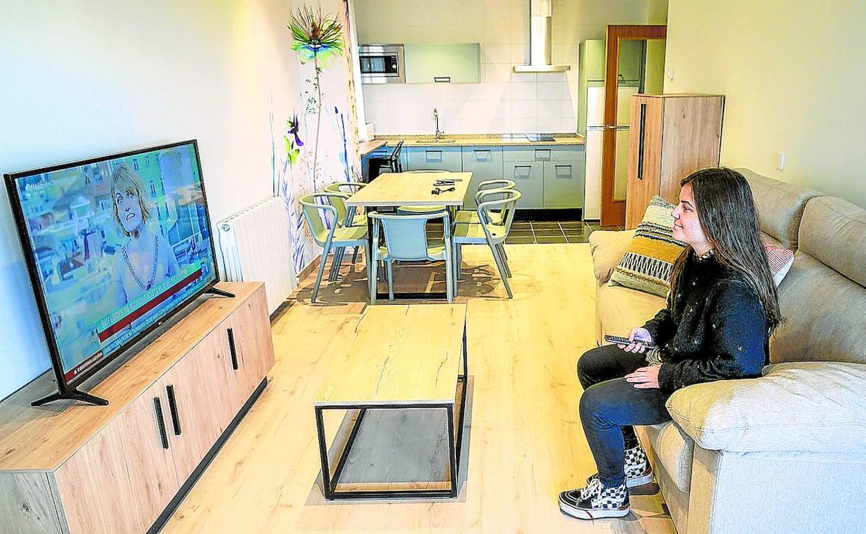 Una joven ve la televisión en la estancia principal de uno de los apartamentos del nuevo alojamiento en Salburua. 