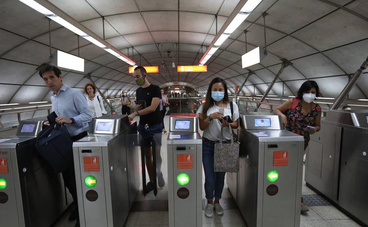 Usuarios de Metro Bilbao pasan la canceladora en una estación. 