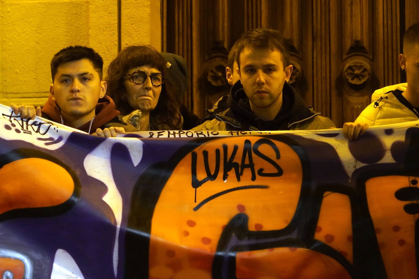 La madre de Lukas Agirre tras la pancarta en recuerdo al joven.