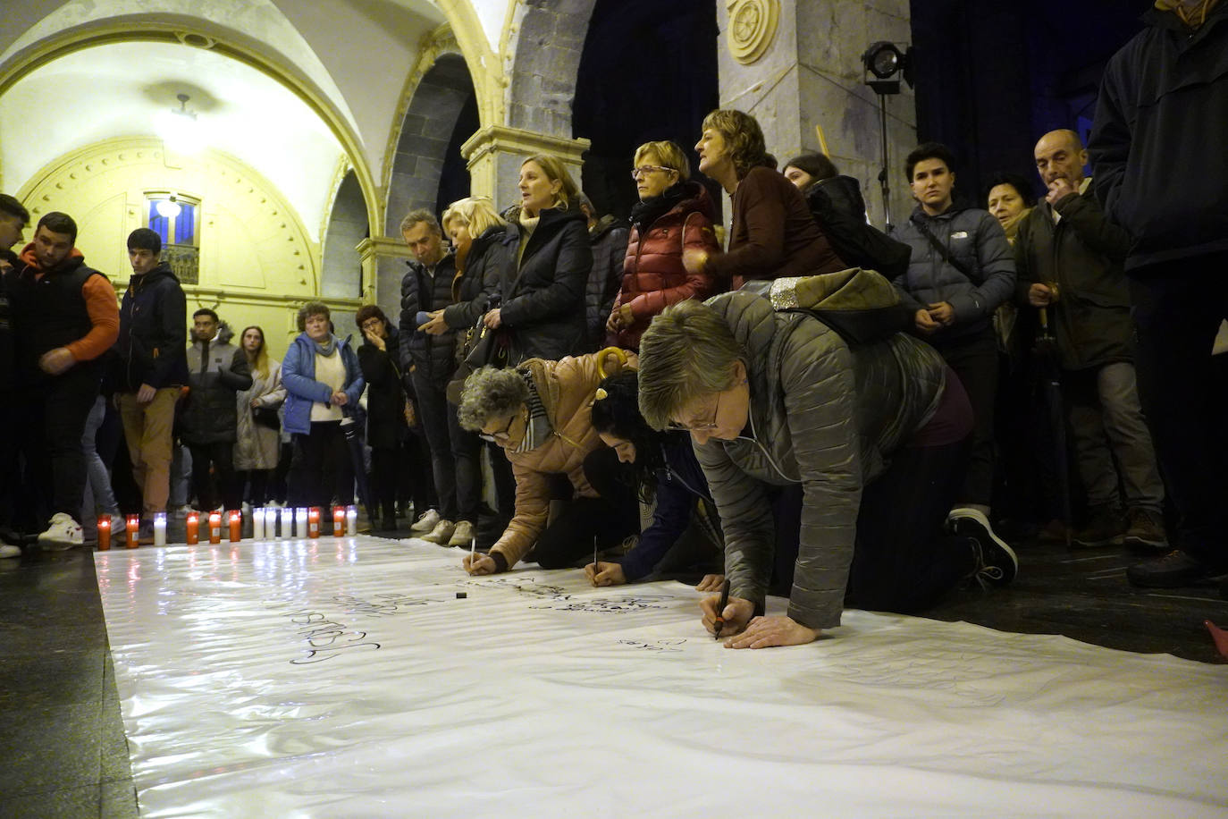 Varias personas escriben unas palabras de afecto a Lukas Agirre en una pancarta.