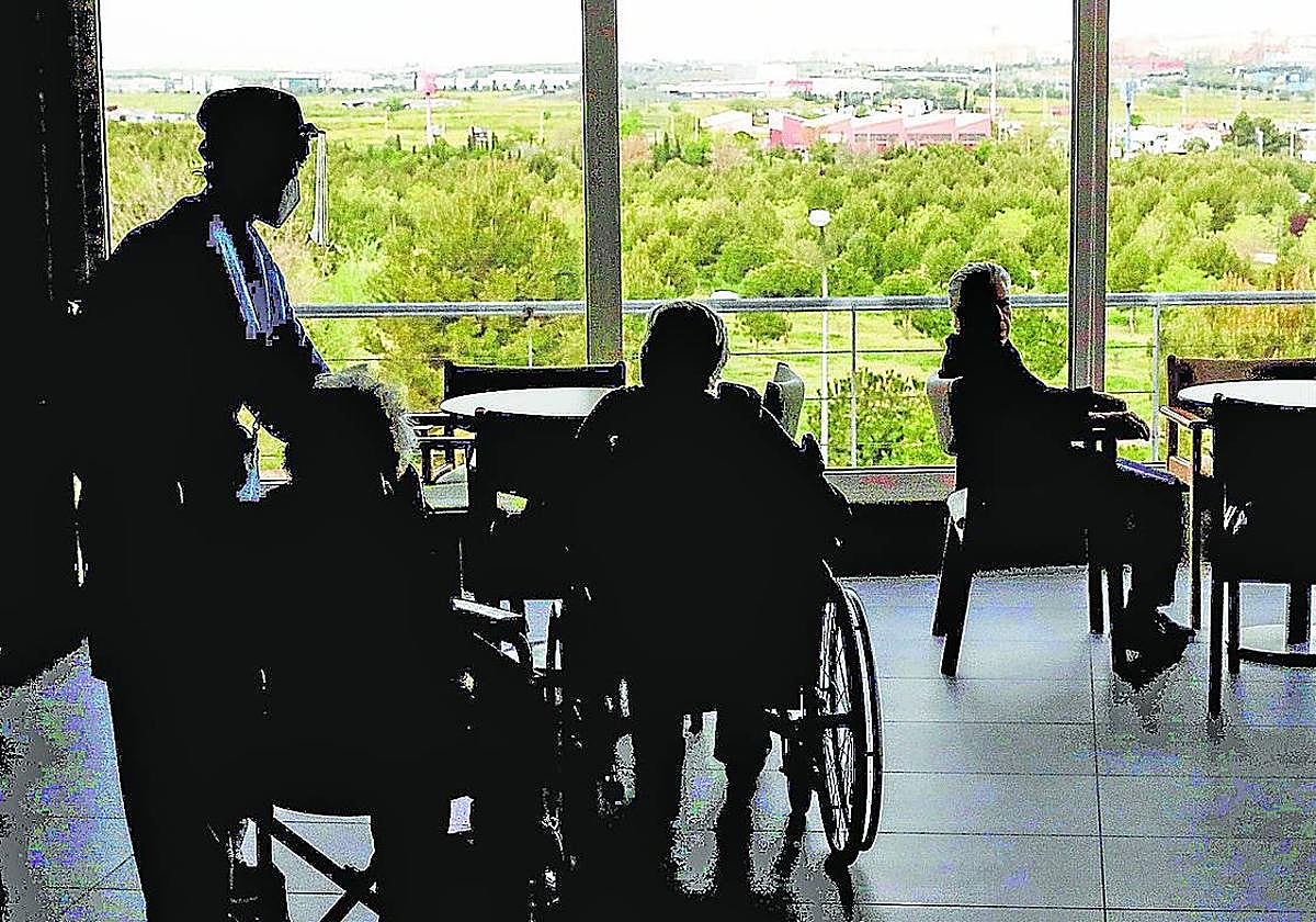 Varias personas mayores, con una cuidadora, en una residencia de ancianos.
