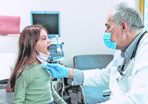 Un pediartra atiende a una niña en un centro de salud.