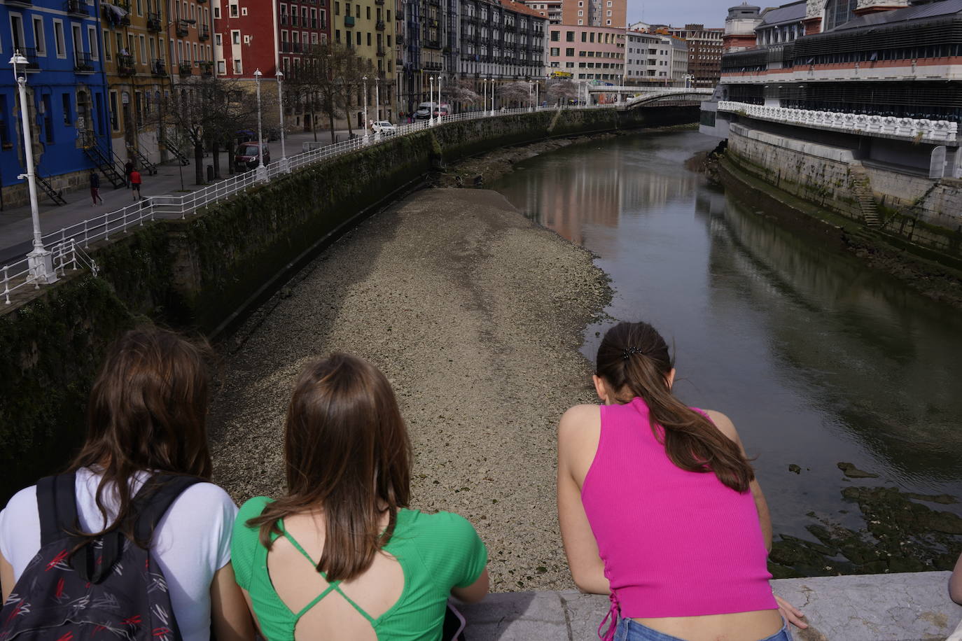 Tres chicas se asoman al puente de San Antón, desde donde han observado los sedimentos visibles del fondo de la ría. IGNACIO PÉREZ