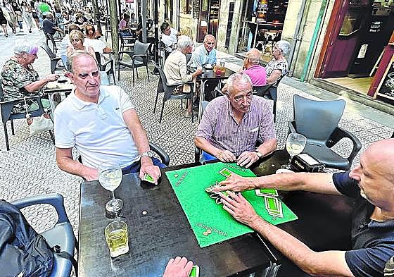 Jubilados juegan a cartas en la terraza de un bar en Bilbao.