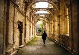 Una joven camina bajo los desnudos arcos del Monasterio de Santa María de Rioseco.