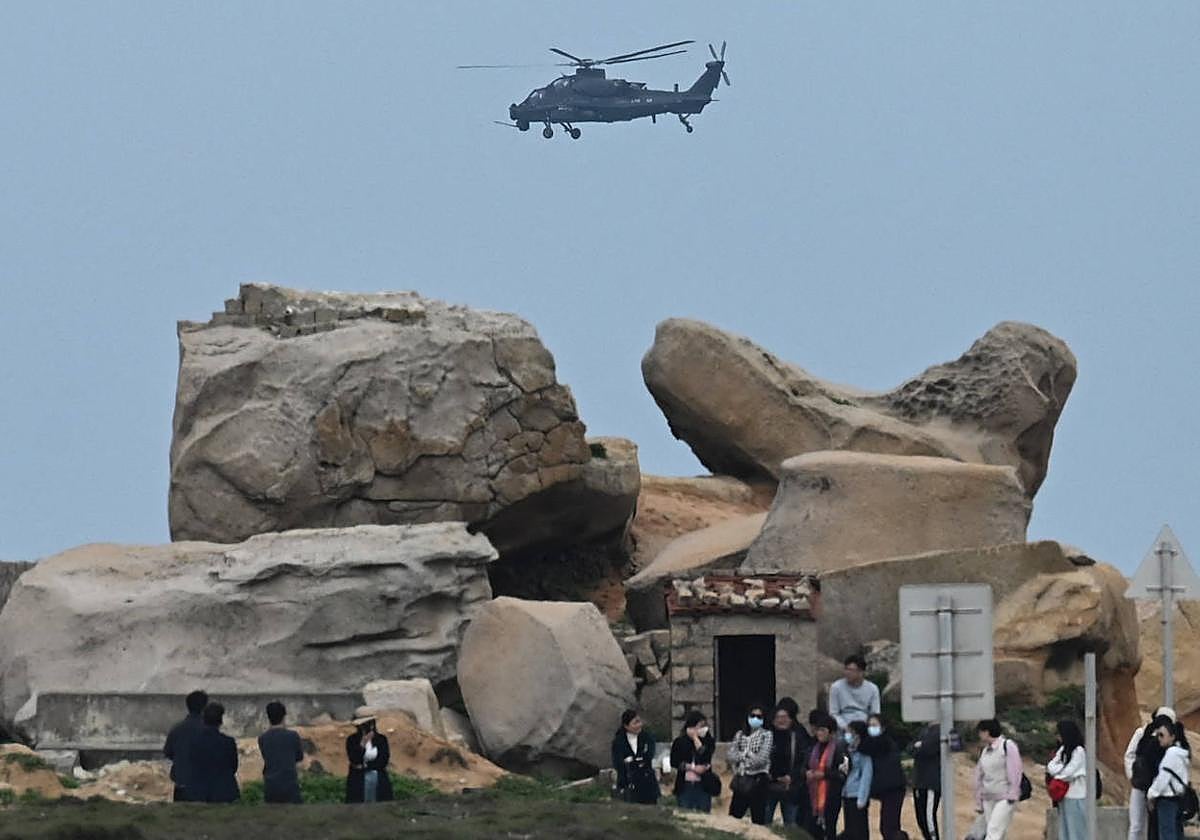 Un helicóptero militar chino sobrevuela a los turistas en un mirador sobre el Estrecho de Taiwán, en la isla de Pingtan