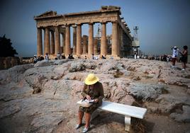 Turista consulta una guía ante el Partenón.