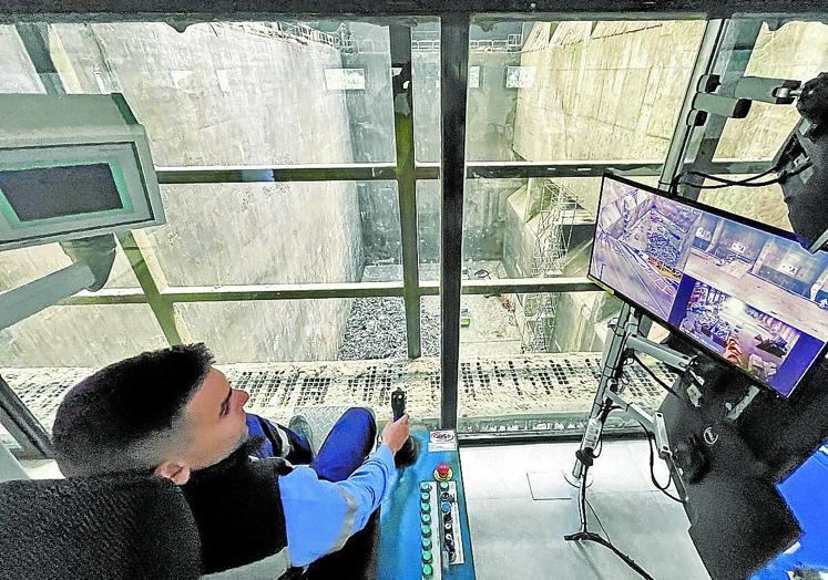 Un operario manipula una de las máquinas situadas al borde del gigantesco foso en el que se depositan los residuos que llegan a la planta.