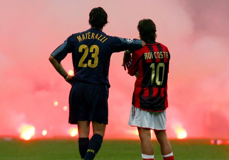 Materazzi y Rui Costa contemplan el despliegue de bengalas en la grada milanesa.