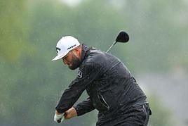 Rahm se dispone a golpear a la bola bajo la lluvia.