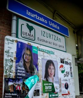 Imagen secundaria 2 - Juan Mari en el frontón, uno de los orgullos de Izurtza. La carretera que atraviesa el pueblo y el panel de anuncios con la cartelería electoral.