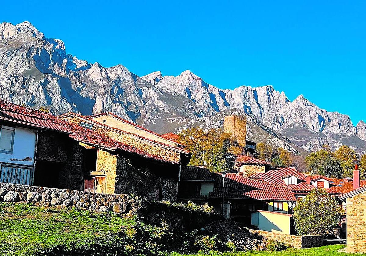 La torre que se alza sobre los tejados de las casas de piedra no logra competir con las cimas que guardan la aldea.