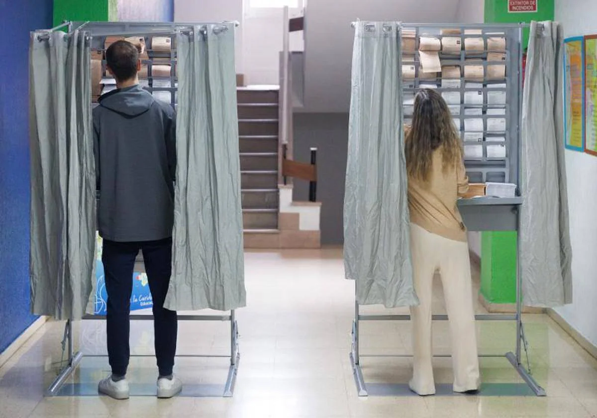 Dos votantes escogen papeleta en un colegio electoral