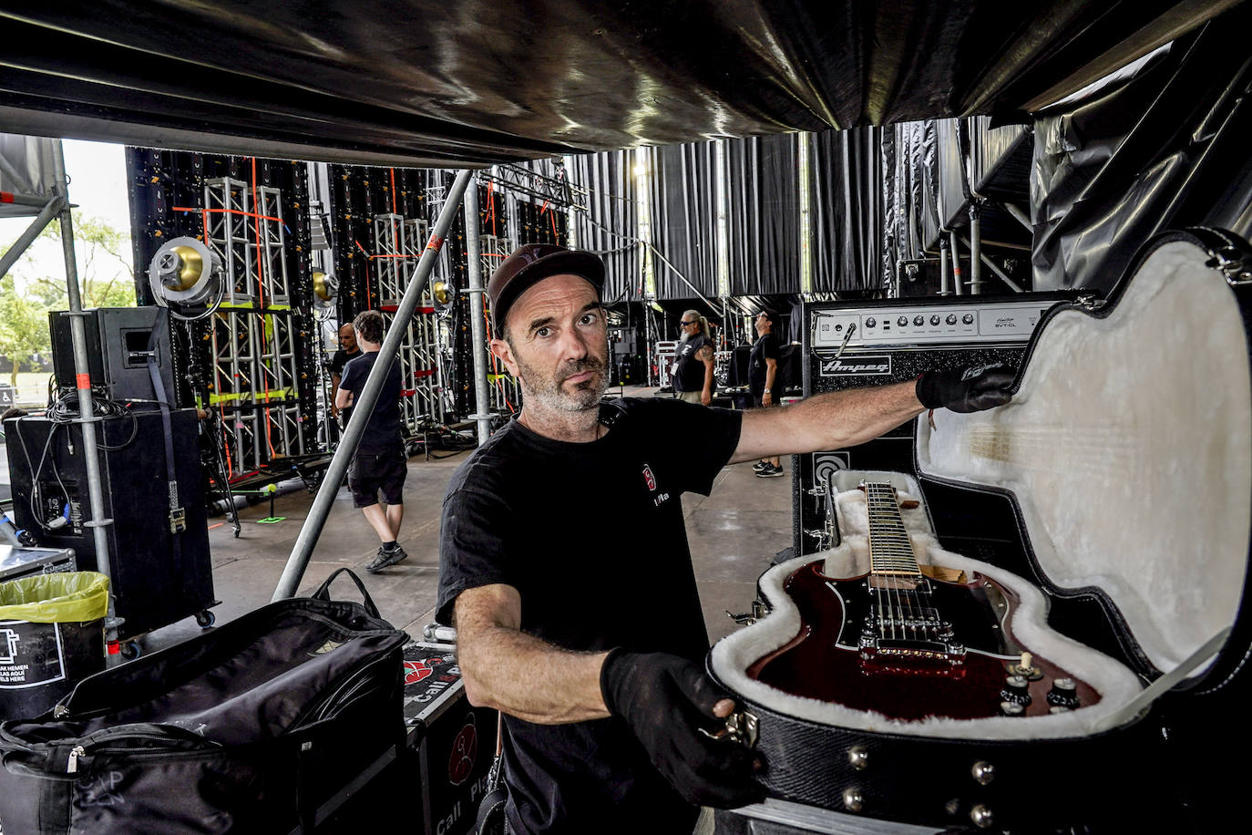 El técnico de backline desenfunda con sumo cuidado la guitarra de uno de los cabezas de cartel.