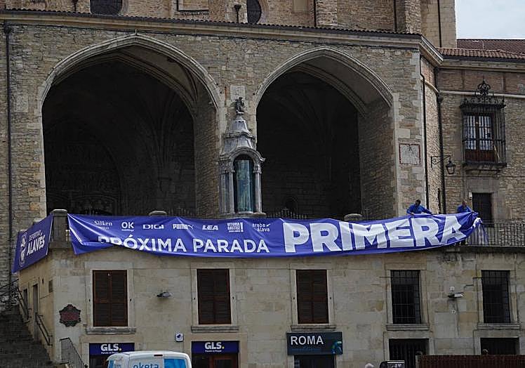 Varios operarios despliegan una pancarta sobre la balconada de San Miguel.