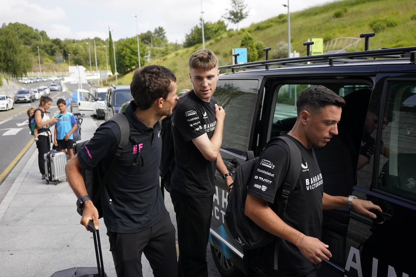 El italiano Antonio Tibero (derecha) entra al coche junto a su compañero, el inglés Fred Wright (centro), que conversa con su compatriota del EF Education - Easypost James Sahw.