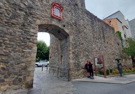 Dos turistas madrileños consultan la información del panel correspondiente a Sanjuanportale, la única puerta de la muralla medieval de Bermeo que se mantiene en pie.