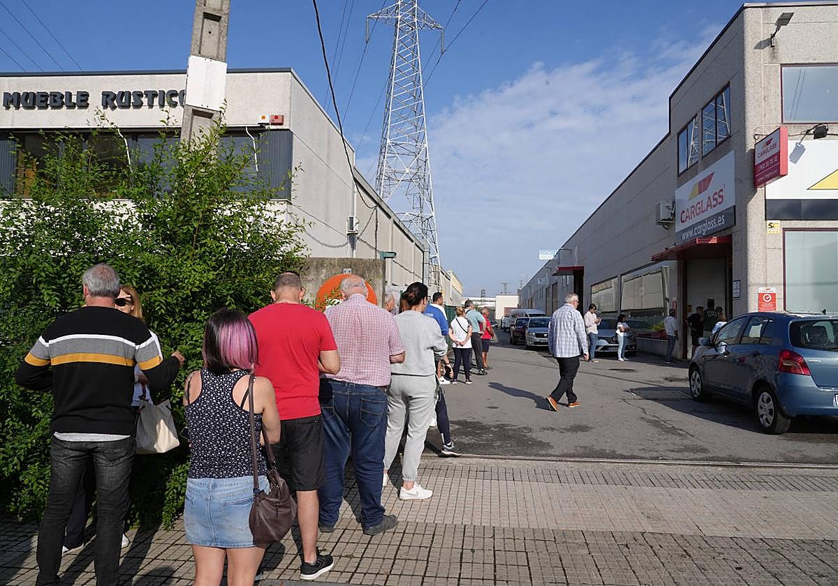 Decenas de vitorianos hacen cola frente a una empresa que repara las lunas de los vehículos.