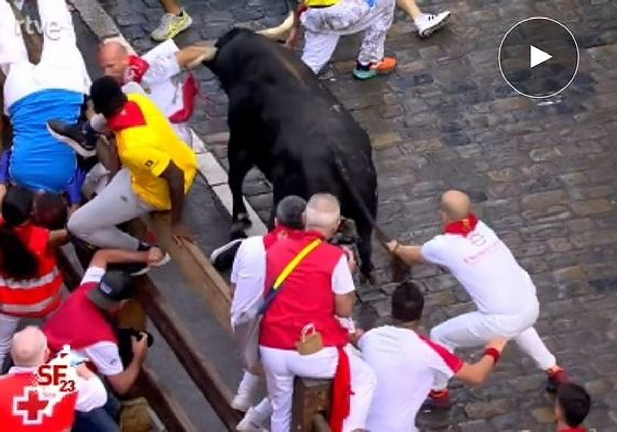 Un toro de la ganadería gaditana de Cebada Gago coge a un mozo a su llegada al callejón durante el quinto encierro de los Sanfermines 2022.