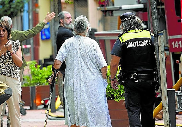 Una mujer desalojada recibe la ayuda de un policía municipal.