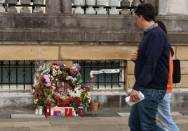 Dos personas observan unas flores y velas en el lugar en el que Lukas Agirre fue apuñalado.