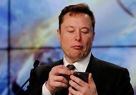 Elon Musk mira su teléfono móvil.