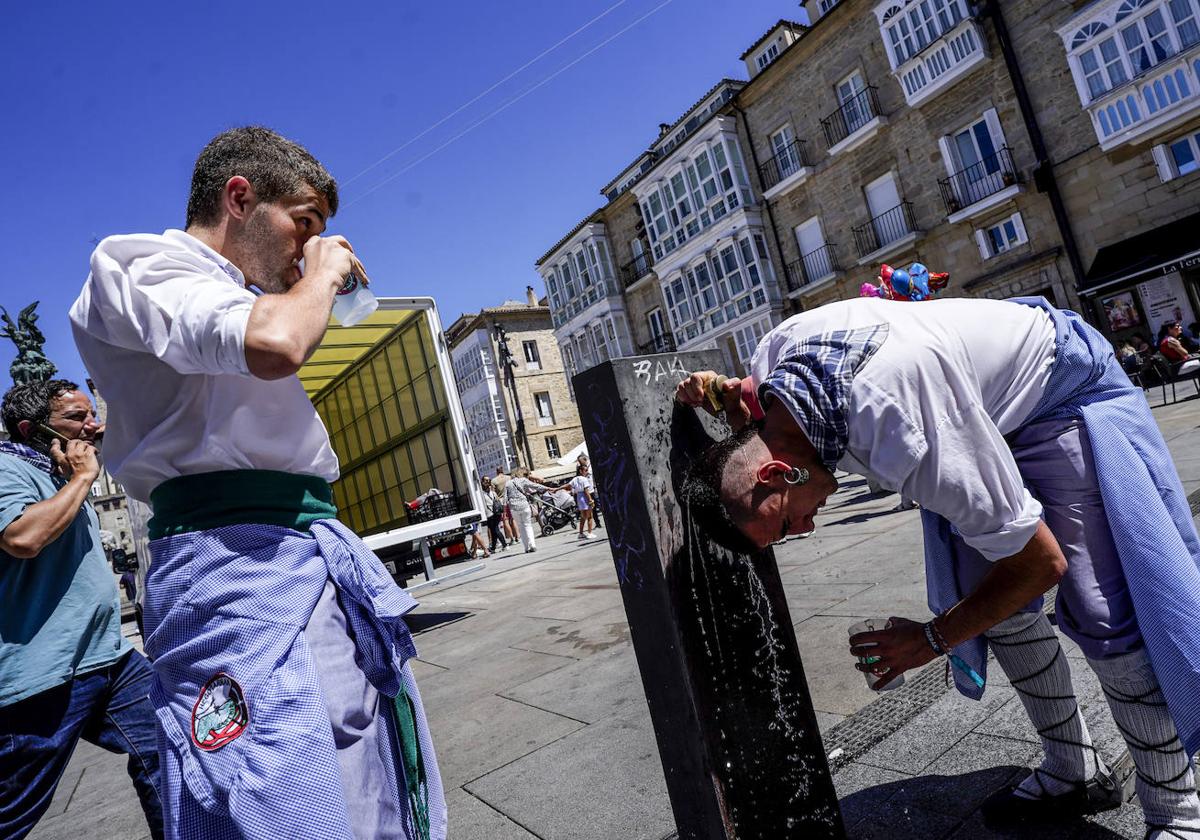 Dos blusas se refrescan en una de las fuentes de la plaza de la Virgen Blanca de Vitoria.