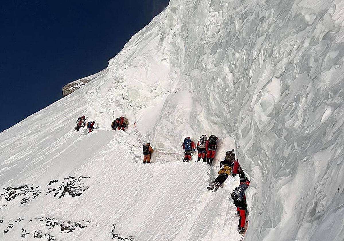 Garraiolariaren gorputza bidean etzanda dago, alpinistak gelditu gabe haren ondotik pasatzen diren bitartean.