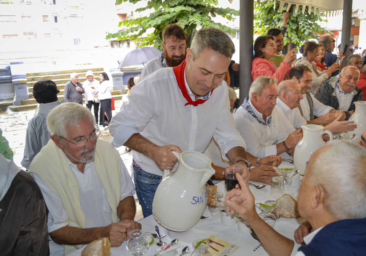 Un participante en la comida de la Cofradía de San Roque de Llodio sirve vino a sus compañeros.