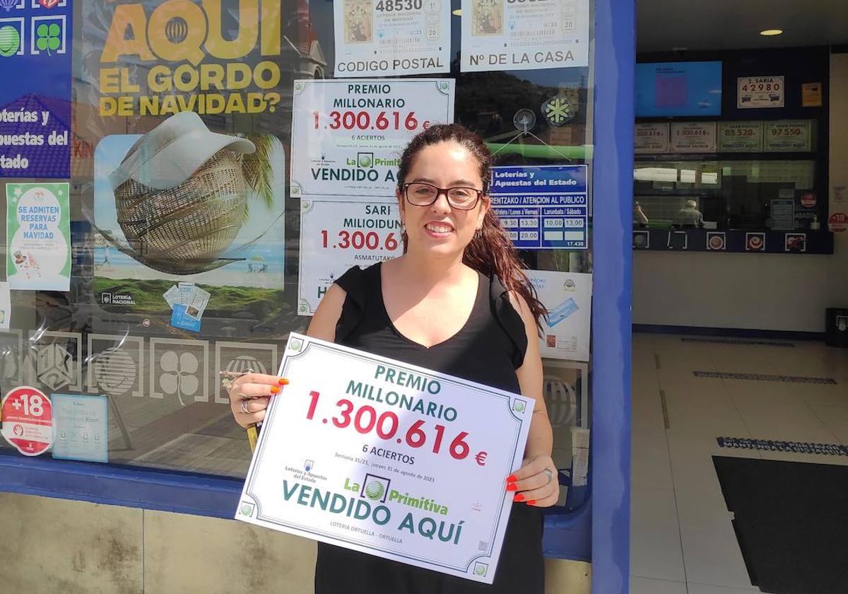 Ariane Díaz, al frente de la Administración de Loterías 1 de Ortuella, posa contenta con el cartel del cuantioso premio.